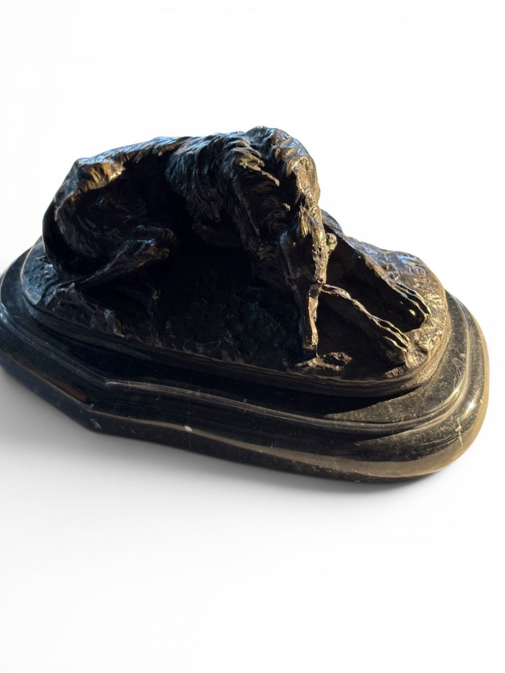 A dark patinated bronze sculpture of a reclining sighthound resting on a moulded dark marble plinth. View II