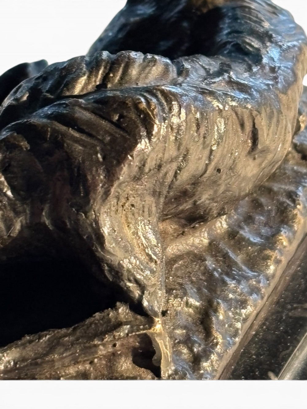 A dark patinated bronze sculpture of a reclining sighthound resting on a moulded dark marble plinth. View IX