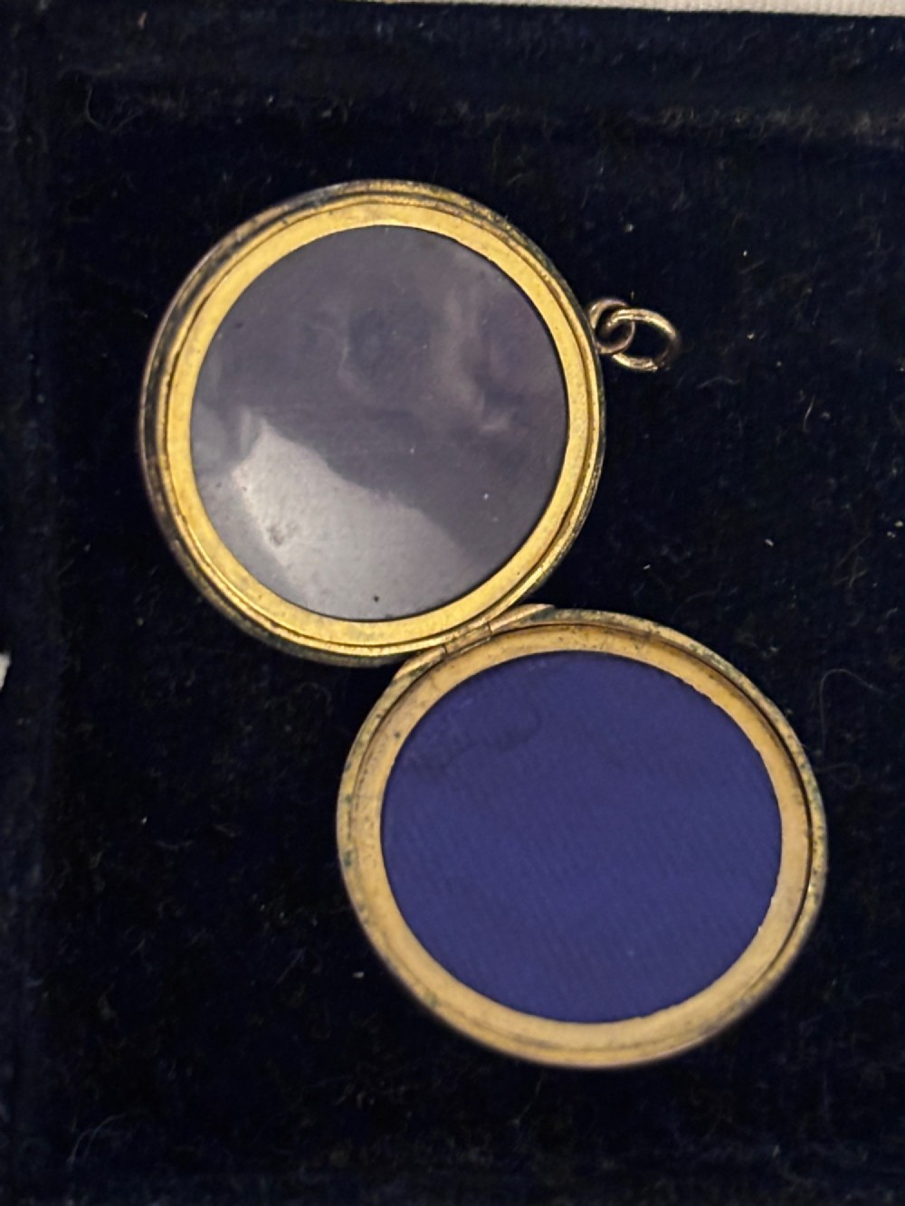 A circular antique gold locket featuring hand-engraved fleur-de-lis emblems and vertical geometric stripes surrounding an unengraved central cartouche. View II