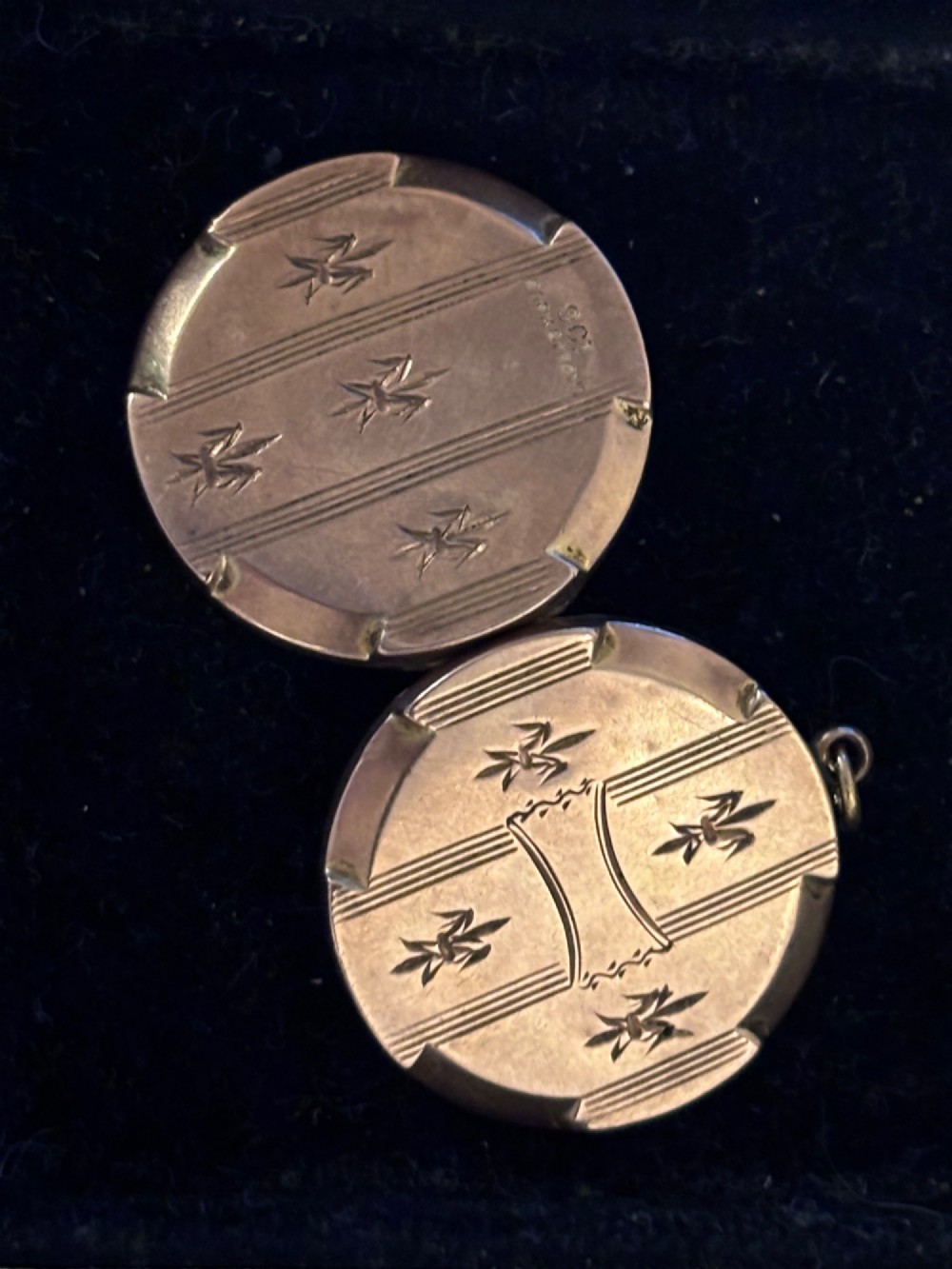 A circular antique gold locket featuring hand-engraved fleur-de-lis emblems and vertical geometric stripes surrounding an unengraved central cartouche. View III