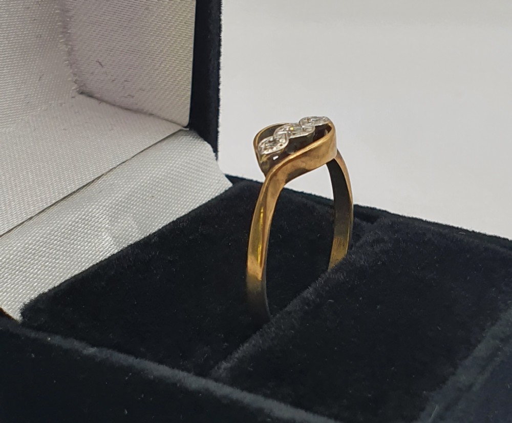 An Art Deco 9ct gold ring featuring a central trilogy of diamonds set in platinum within a fluid bypass motif. View III