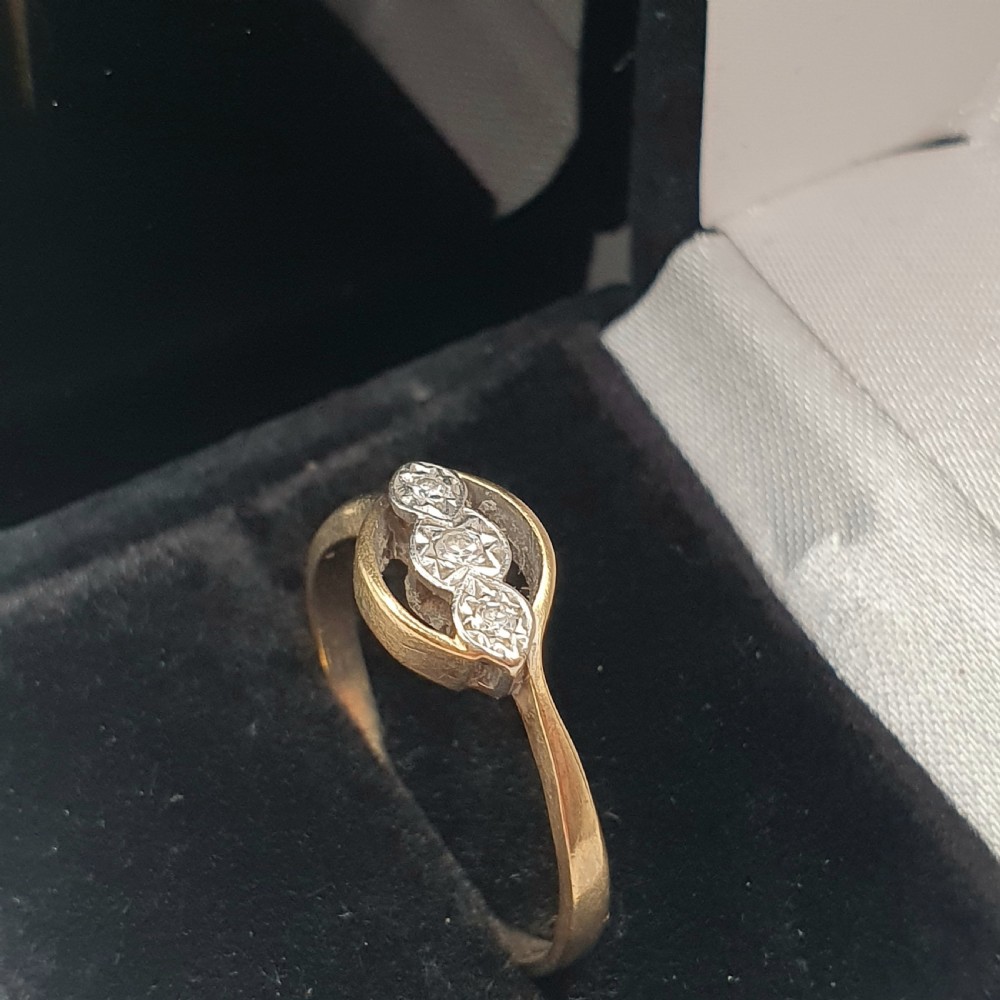 An Art Deco 9ct gold ring featuring a central trilogy of diamonds set in platinum within a fluid bypass motif. View VII