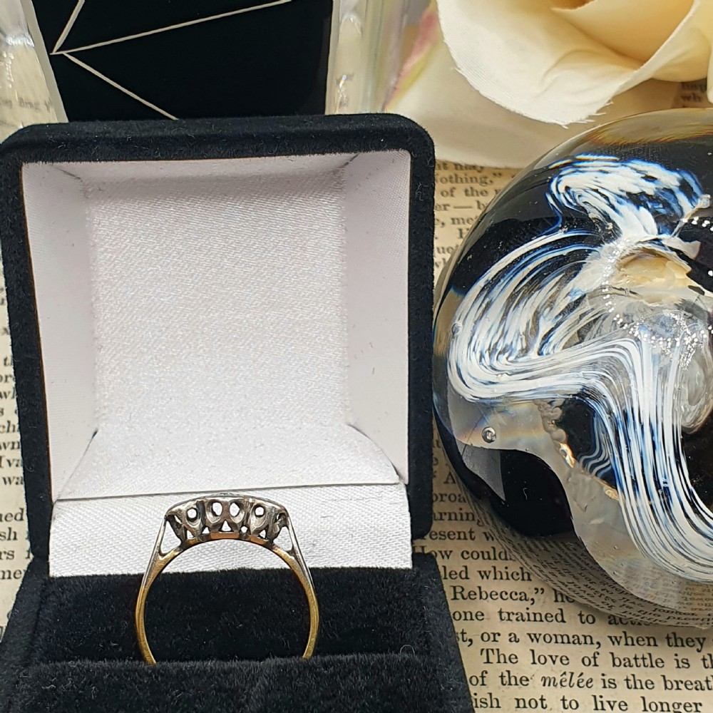 An Art Deco trilogy ring featuring three star-set round diamonds in a platinum setting on an 18ct yellow gold band. View II