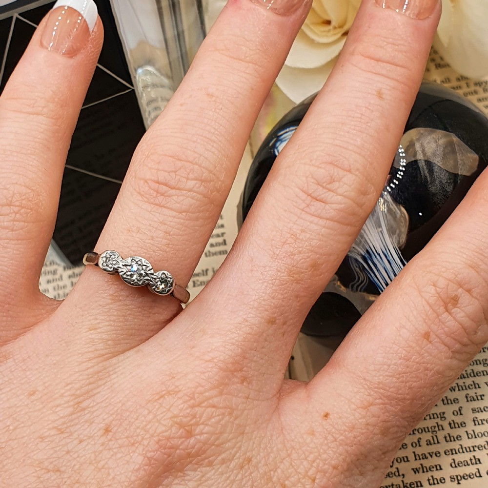 An Art Deco trilogy ring featuring three star-set round diamonds in a platinum setting on an 18ct yellow gold band. View VIII