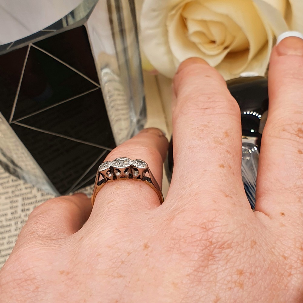 An Art Deco trilogy ring featuring three star-set round diamonds in a platinum setting on an 18ct yellow gold band. View IX