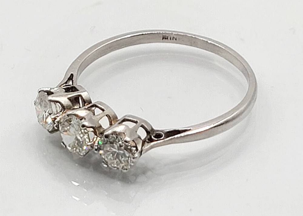 An Art Deco platinum ring featuring three round diamonds set side-by-side in claw mounts along a plain band. View VI