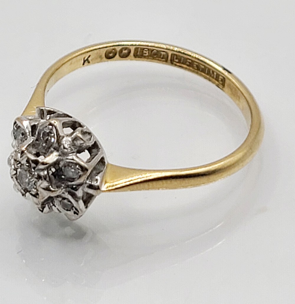 A vintage 18ct yellow gold and white metal cluster ring featuring a central diamond surrounded by a floral halo of smaller diamonds. View VI