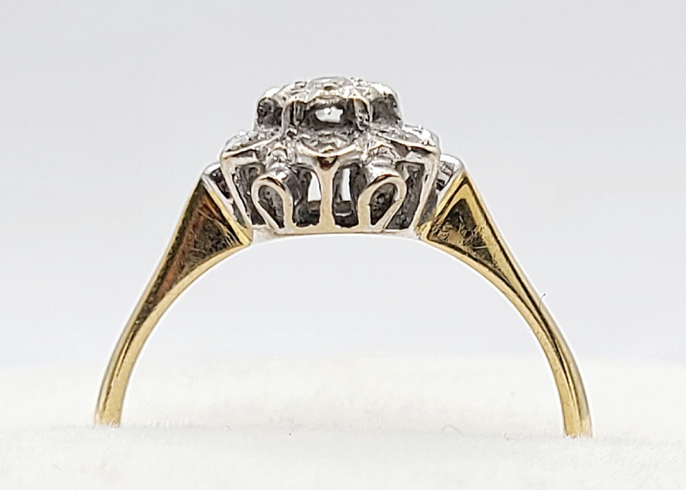 A vintage 18ct yellow gold and white metal cluster ring featuring a central diamond surrounded by a floral halo of smaller diamonds. View VII