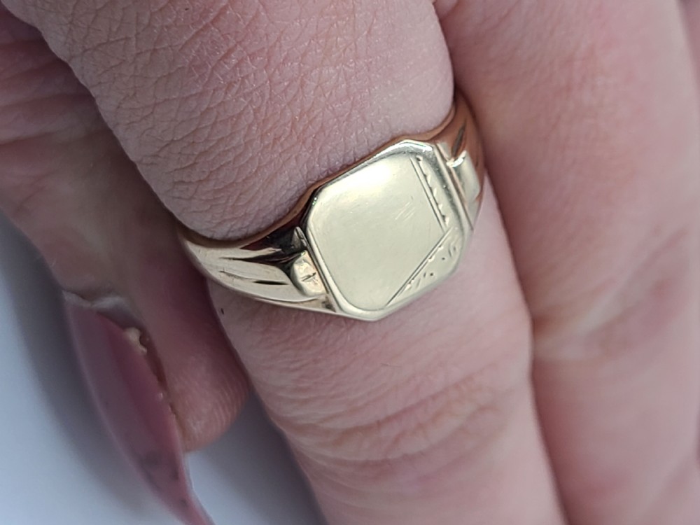 A close-up view of an antique 9ct gold art deco signet ring featuring geometric engraving on the shoulders and a rectangular face. View III