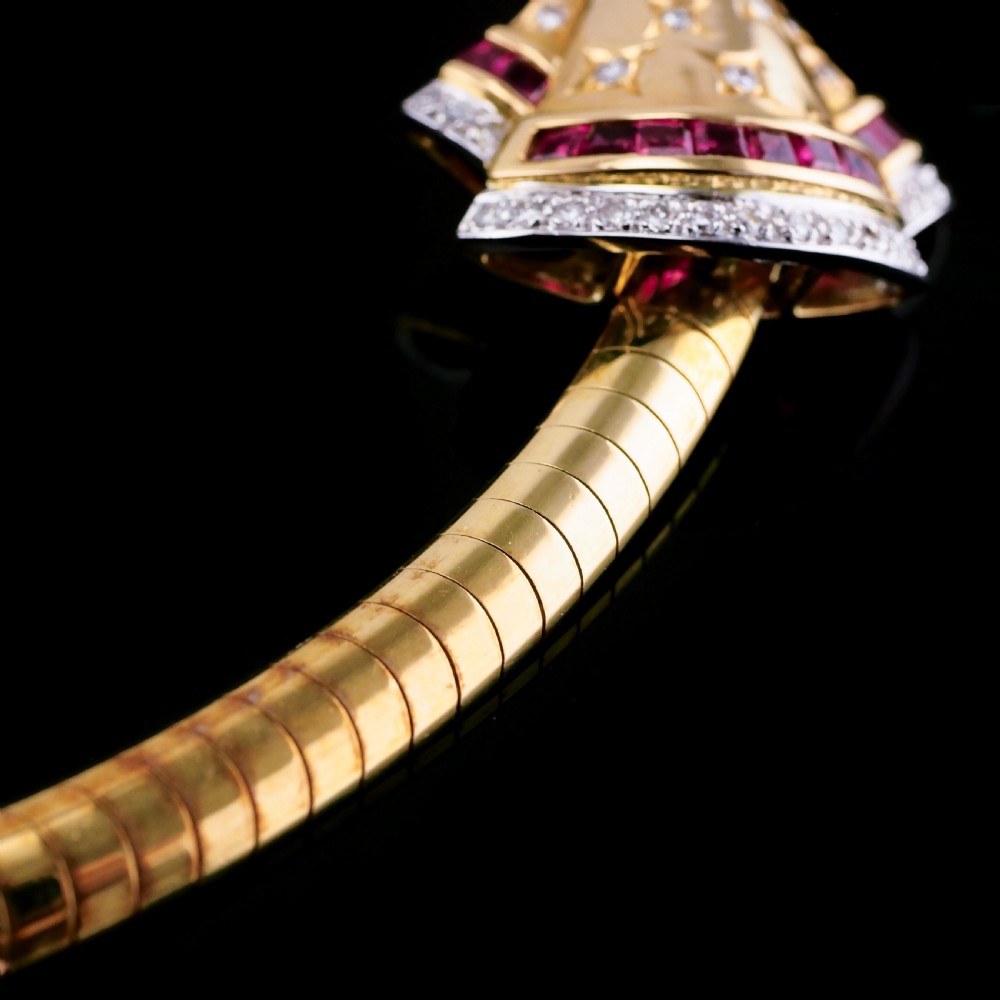 A structured 18k yellow gold collar necklace featuring a central bow motif accented with rubies and star-set diamonds above a teardrop pearl. View XVII