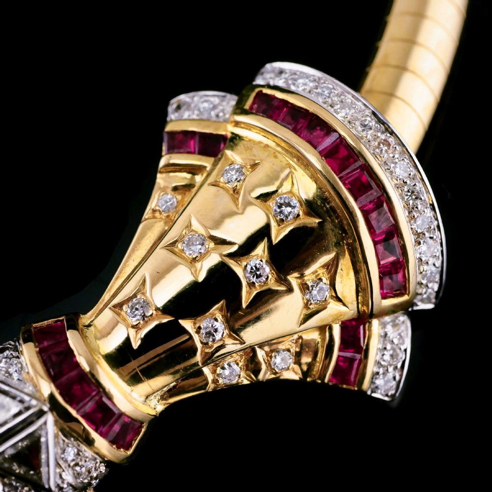 A structured 18k yellow gold collar necklace featuring a central bow motif accented with rubies and star-set diamonds above a teardrop pearl. View XIX
