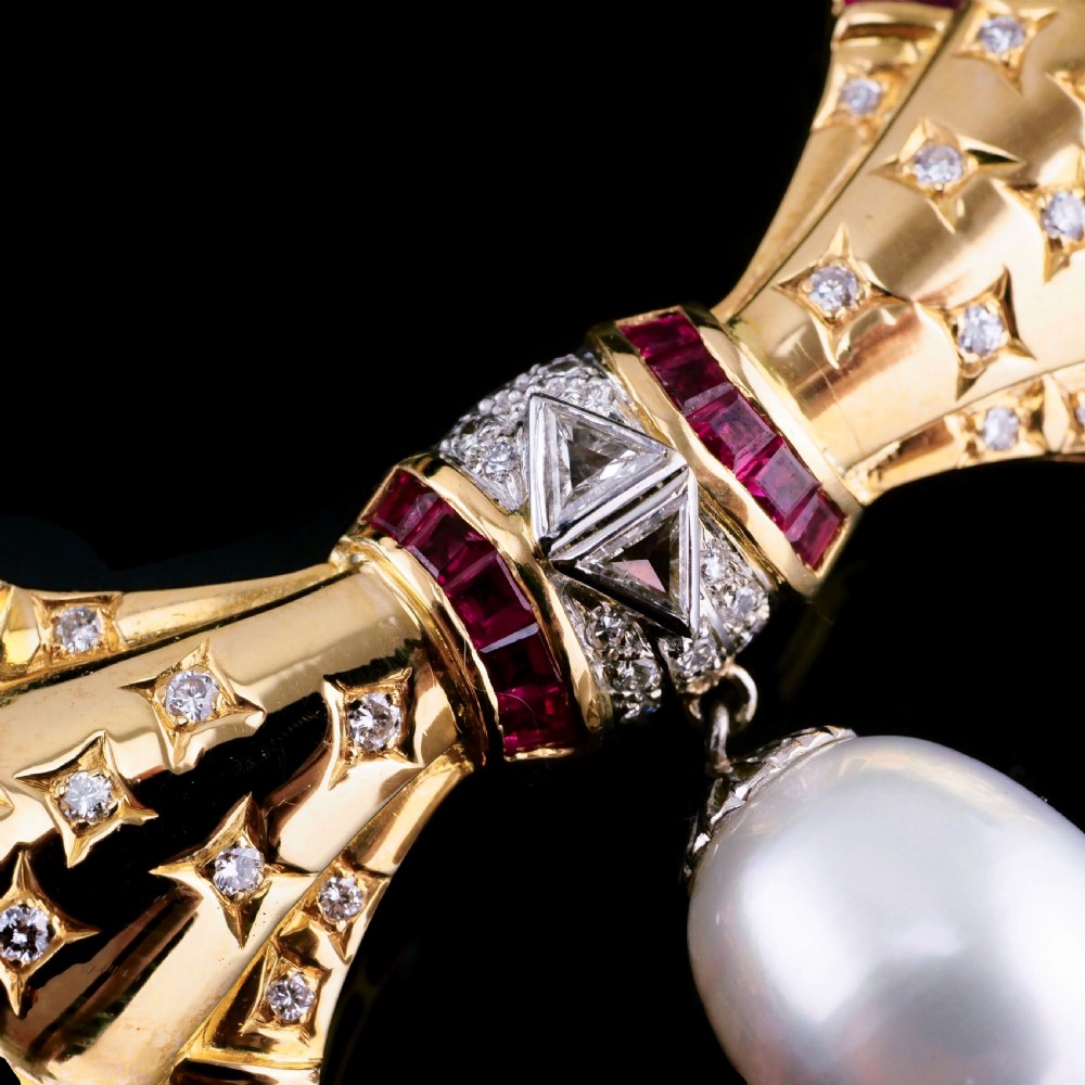 A structured 18k yellow gold collar necklace featuring a central bow motif accented with rubies and star-set diamonds above a teardrop pearl. View XX