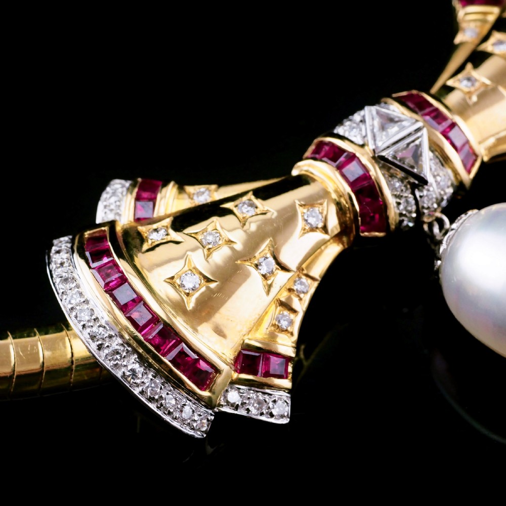 A structured 18k yellow gold collar necklace featuring a central bow motif accented with rubies and star-set diamonds above a teardrop pearl. View XXII
