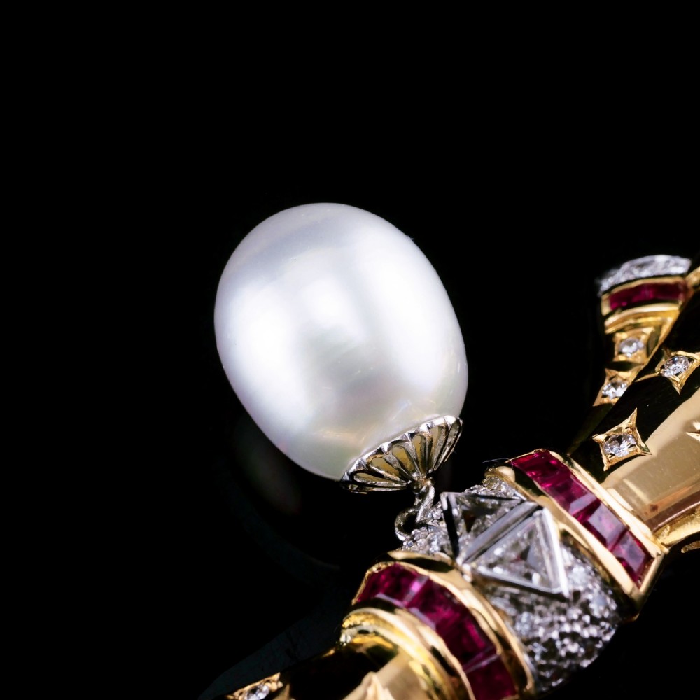 A structured 18k yellow gold collar necklace featuring a central bow motif accented with rubies and star-set diamonds above a teardrop pearl. View XXIII