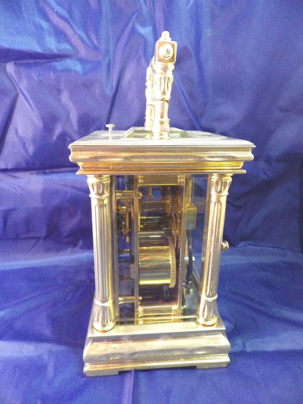 A nineteenth-century French gilt brass repeating carriage clock featuring fluted column corners, bevelled glass panels, and an ornate gilt foliate mask surrounding a central white enamel dial. View VI
