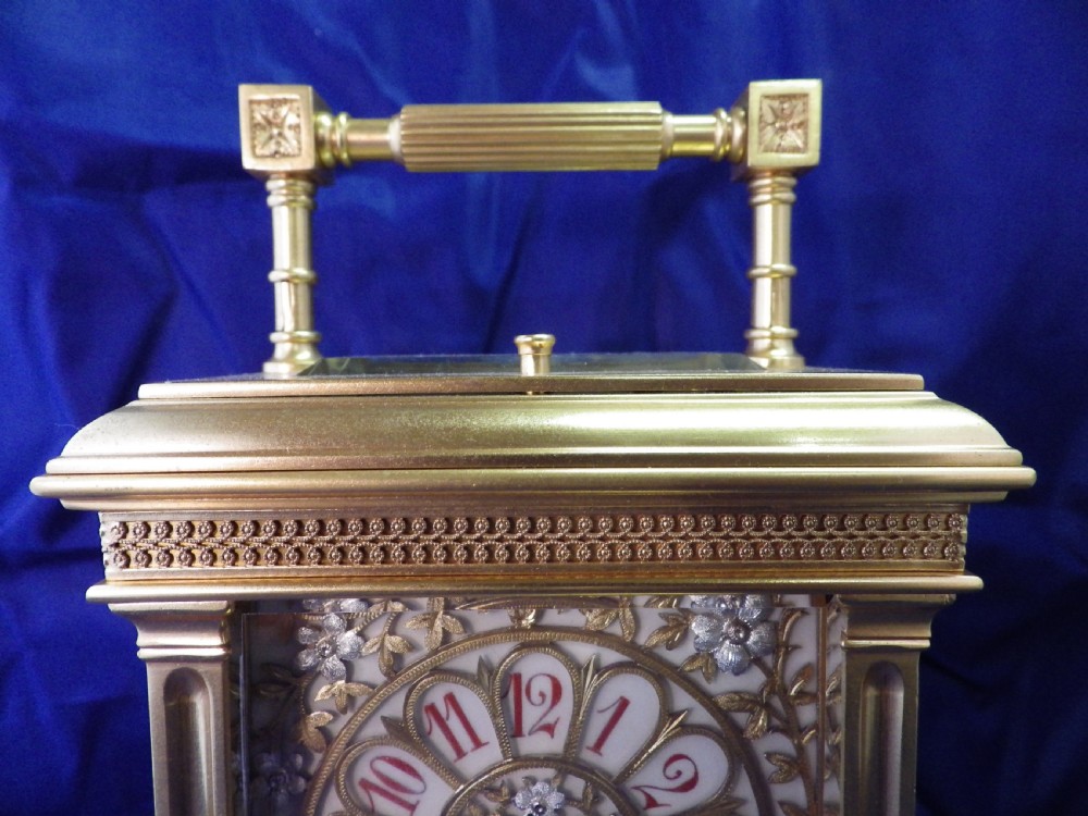 A gilt brass French repeating carriage clock featuring fluted corner columns, an intricate floral dial plate with enamel numerals, and a top carrying handle. View III