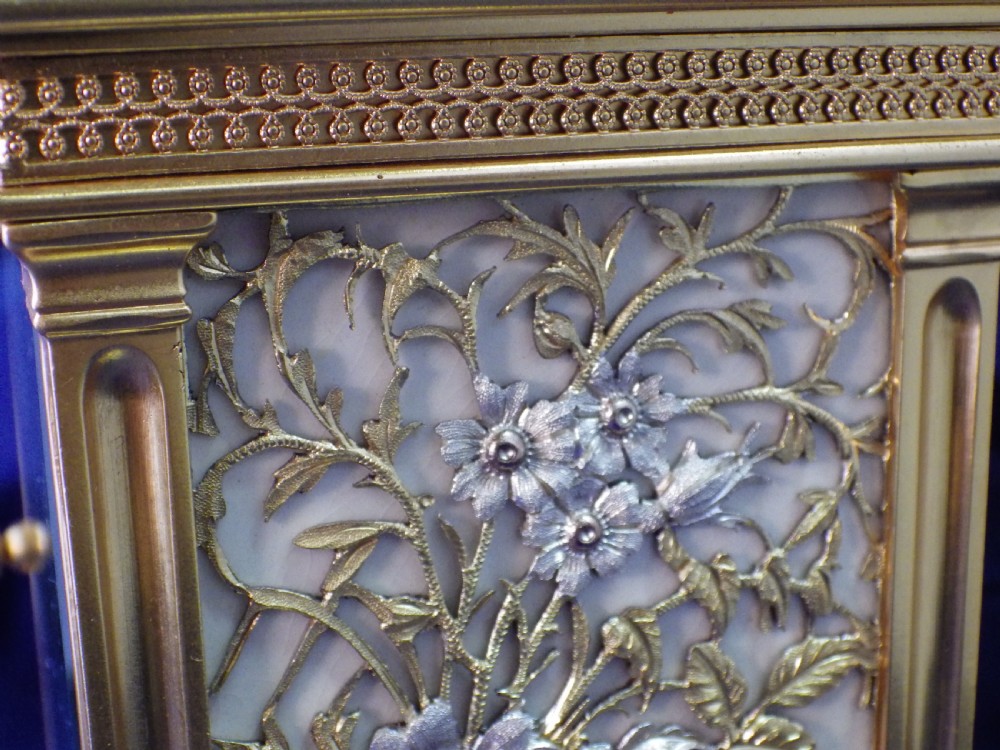 A gilt brass French repeating carriage clock featuring fluted corner columns, an intricate floral dial plate with enamel numerals, and a top carrying handle. View IX