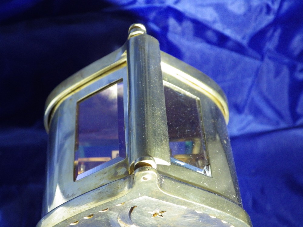 A brass French carriage clock featuring an arched canopy with an engraved crescent moon and star motif above a white enamel dial with Roman numerals. View III