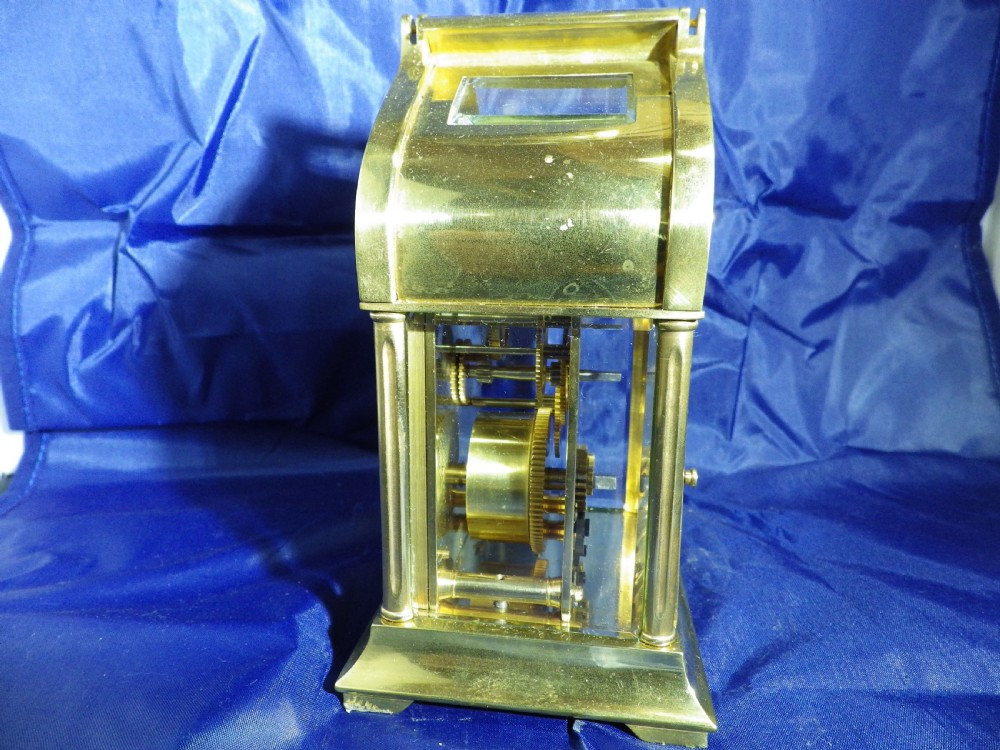 A brass French carriage clock featuring an arched canopy with an engraved crescent moon and star motif above a white enamel dial with Roman numerals. View IV