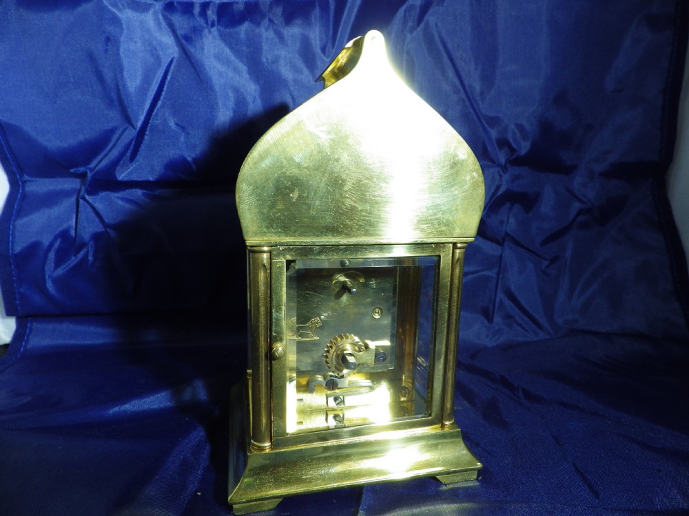 A brass French carriage clock featuring an arched canopy with an engraved crescent moon and star motif above a white enamel dial with Roman numerals. View V