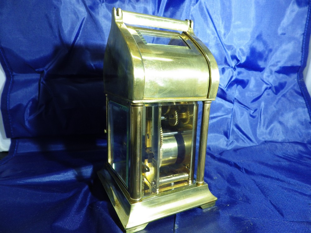 A brass French carriage clock featuring an arched canopy with an engraved crescent moon and star motif above a white enamel dial with Roman numerals. View VI