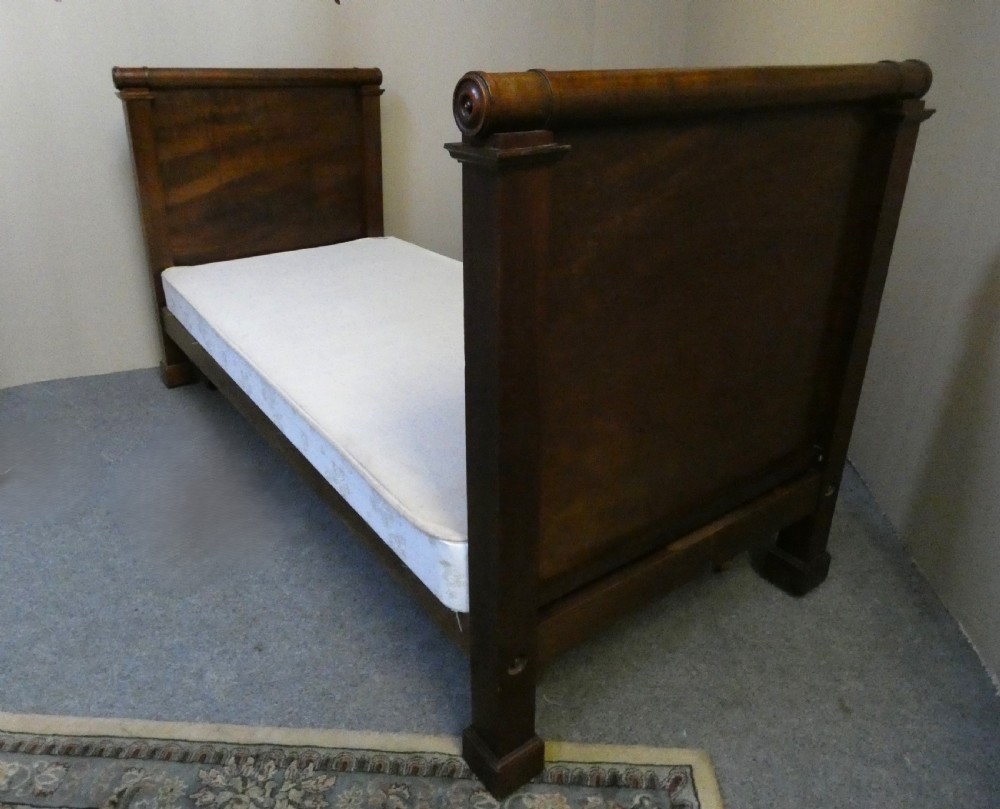 An antique dark mahogany single bed frame featuring a rolled scroll cresting rail on the headboard and footboard. View II