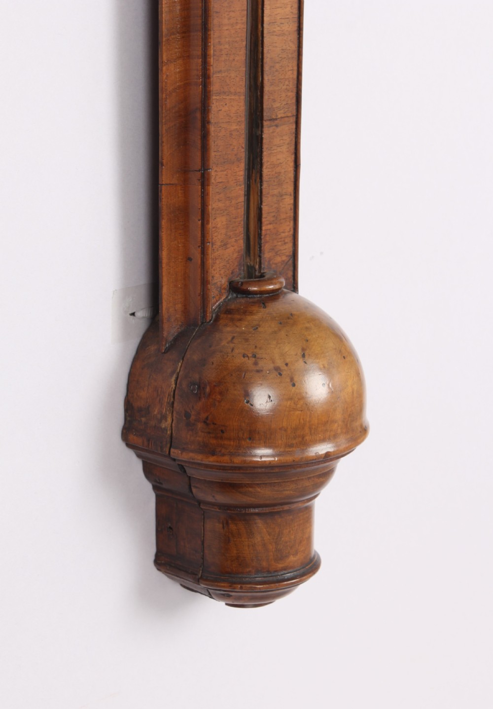 An early 18th-century walnut stick barometer featuring an arched brass register plate, turned side pillars, brass finials, and a turned hemispherical cistern cover. View IV