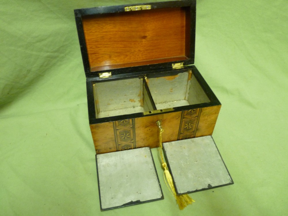 An open Victorian burr walnut tea caddy showcasing two interior lidded compartments and exterior geometric marquetry inlay. View V