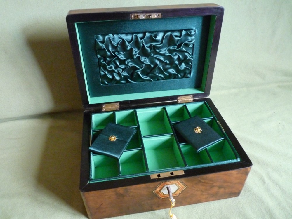 An open Victorian burr walnut jewellery box with a green silk lining, partitioned tray, and mother-of-pearl escutcheon. View IV