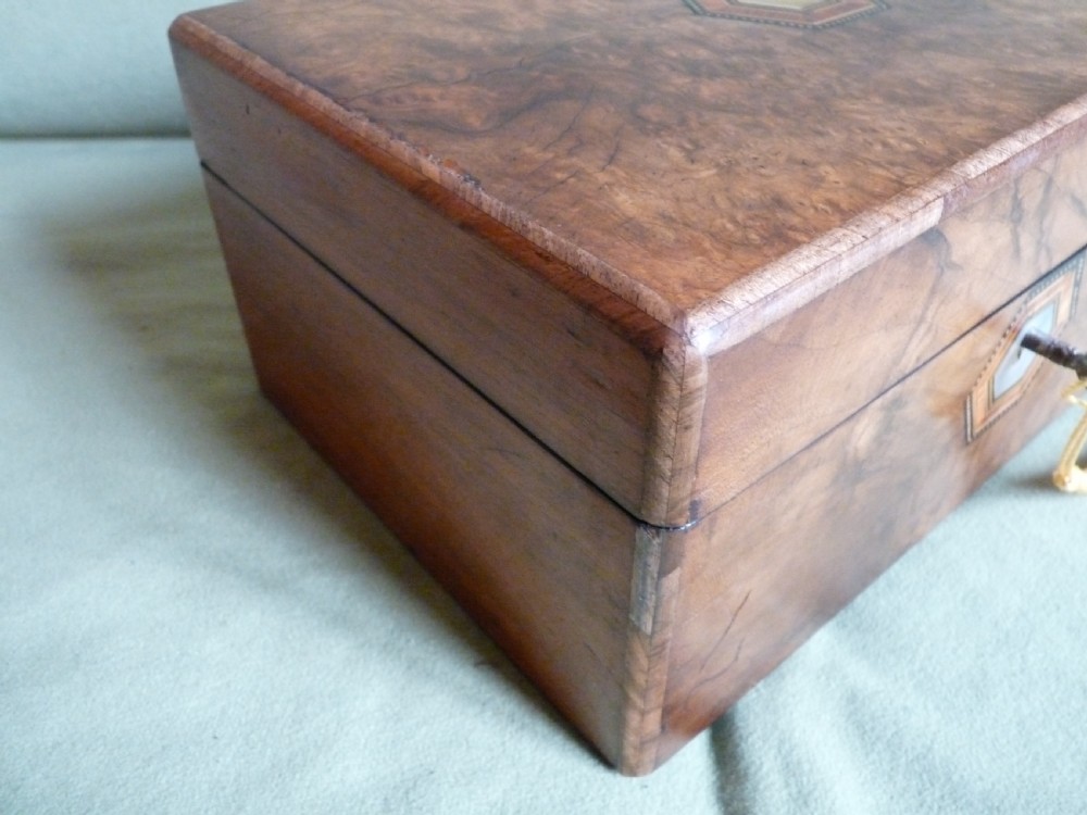 An open Victorian burr walnut jewellery box with a green silk lining, partitioned tray, and mother-of-pearl escutcheon. View VI