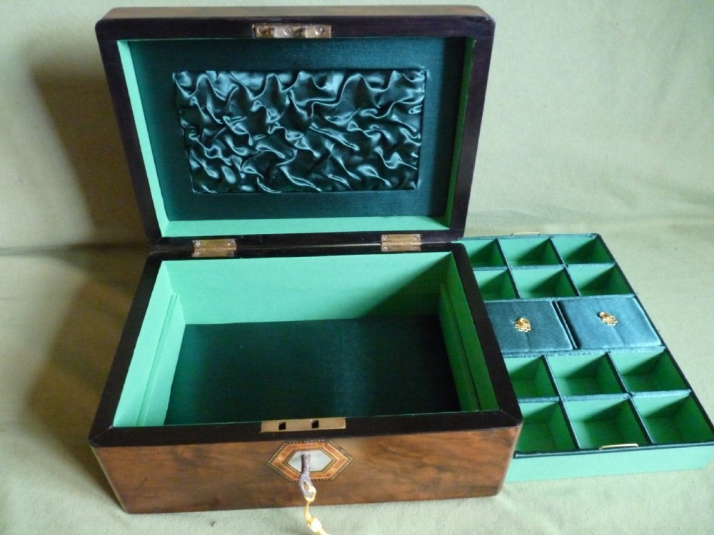 An open Victorian burr walnut jewellery box with a green silk lining, partitioned tray, and mother-of-pearl escutcheon. View VII