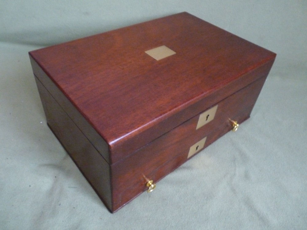 An open mahogany jewellery box featuring a pink-lined interior with tiered compartments, a lower drawer, and brass fittings. View II