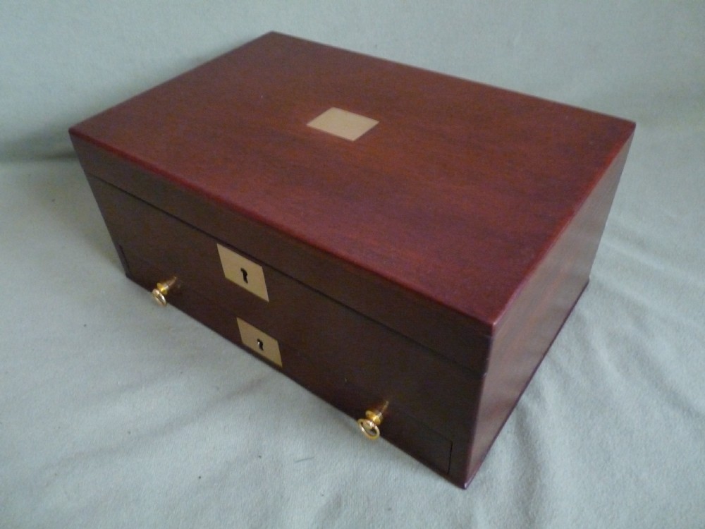 An open mahogany jewellery box featuring a pink-lined interior with tiered compartments, a lower drawer, and brass fittings. View VIII