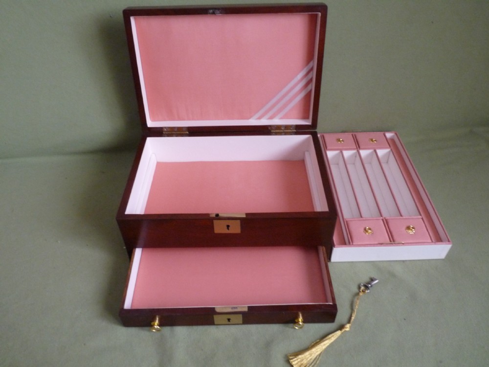 An open mahogany jewellery box featuring a pink-lined interior with tiered compartments, a lower drawer, and brass fittings. View IX