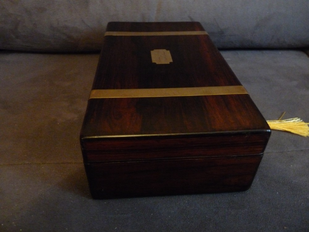 A dark rosewood rectangular box featuring polished brass straps across the lid and front with a central brass plaque and keyhole. View V