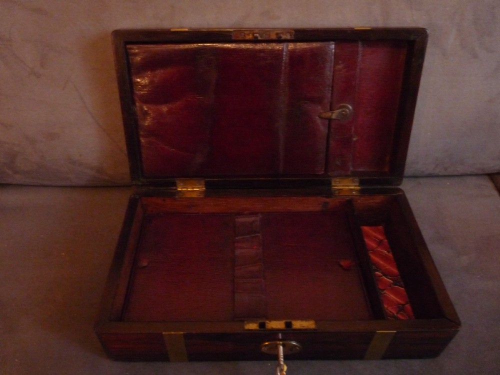 A dark rosewood rectangular box featuring polished brass straps across the lid and front with a central brass plaque and keyhole. View VI