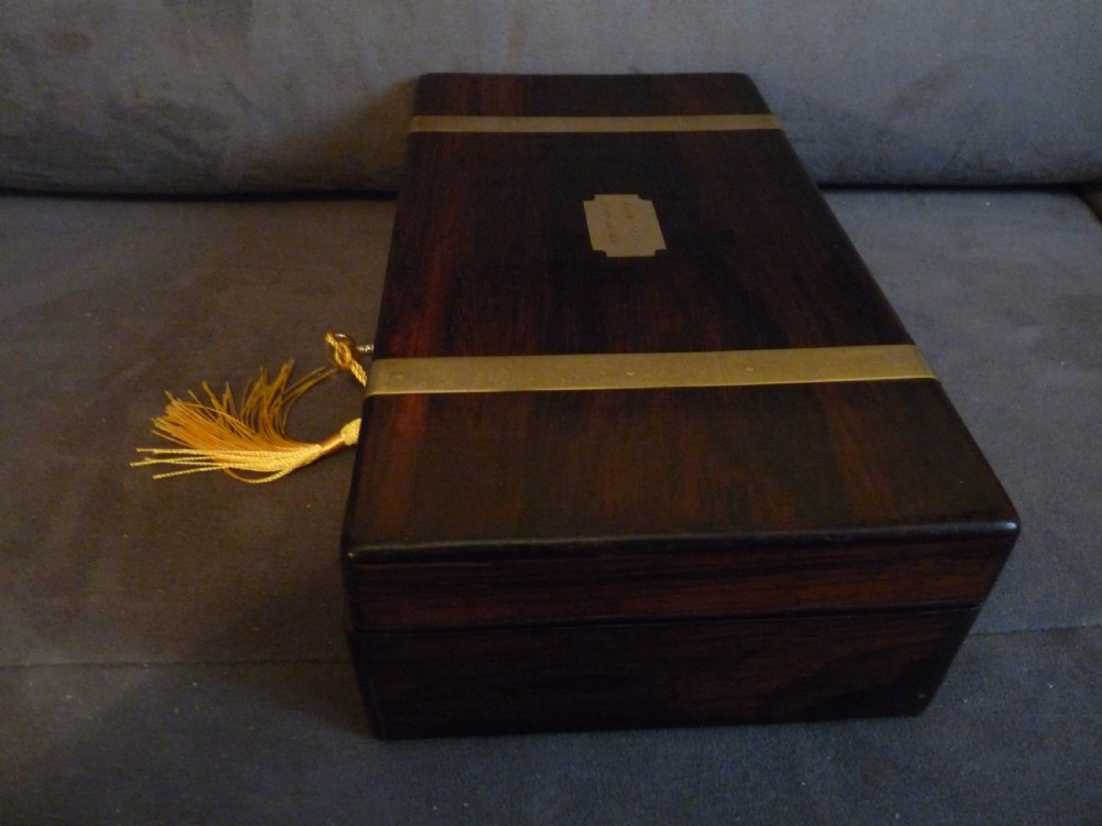 A dark rosewood rectangular box featuring polished brass straps across the lid and front with a central brass plaque and keyhole. View X
