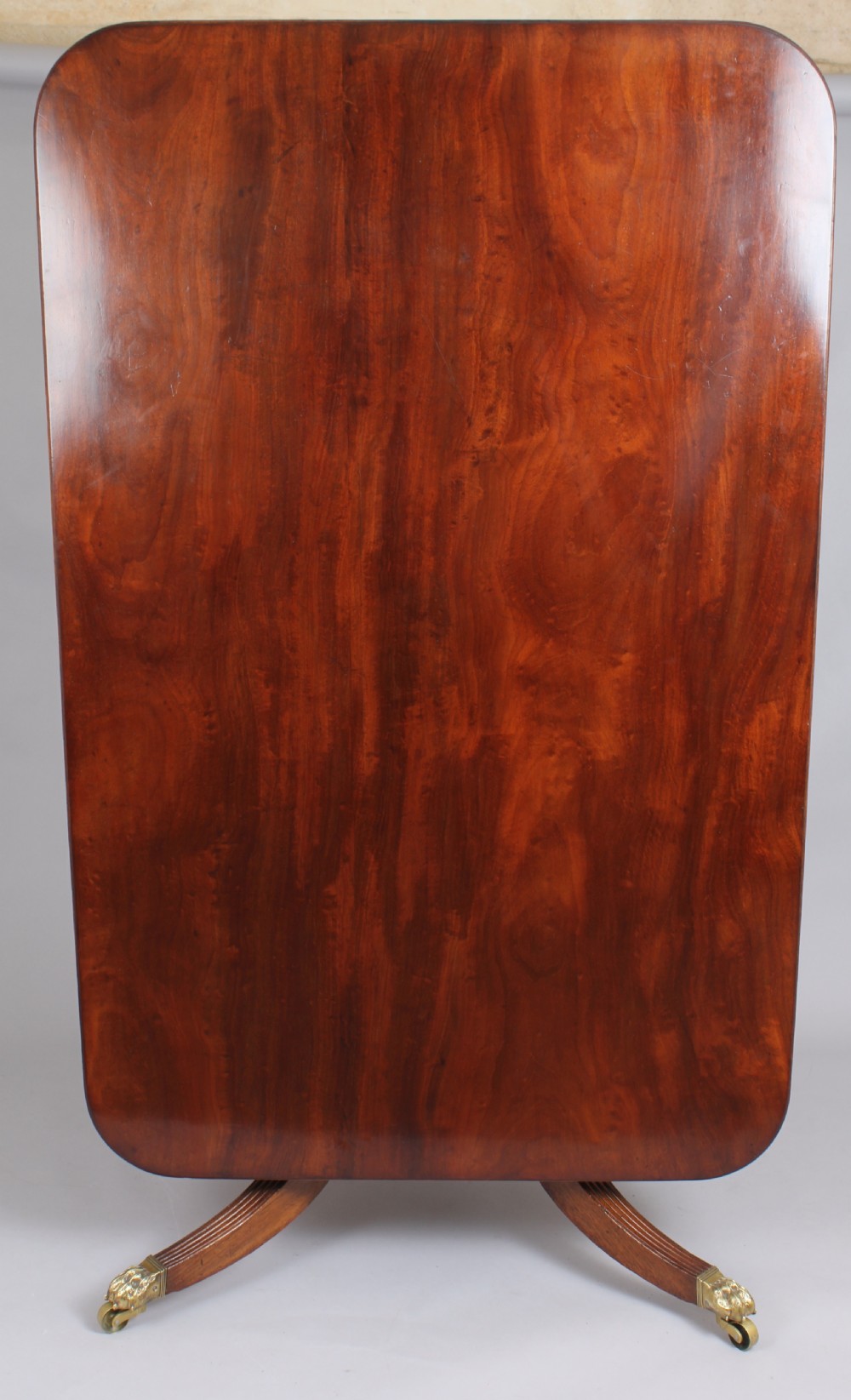 A George IV mahogany breakfast table featuring a polished rectangular top with rounded corners, supported by a spiral-carved pedestal and four reeded legs with brass lion paw castors. View III