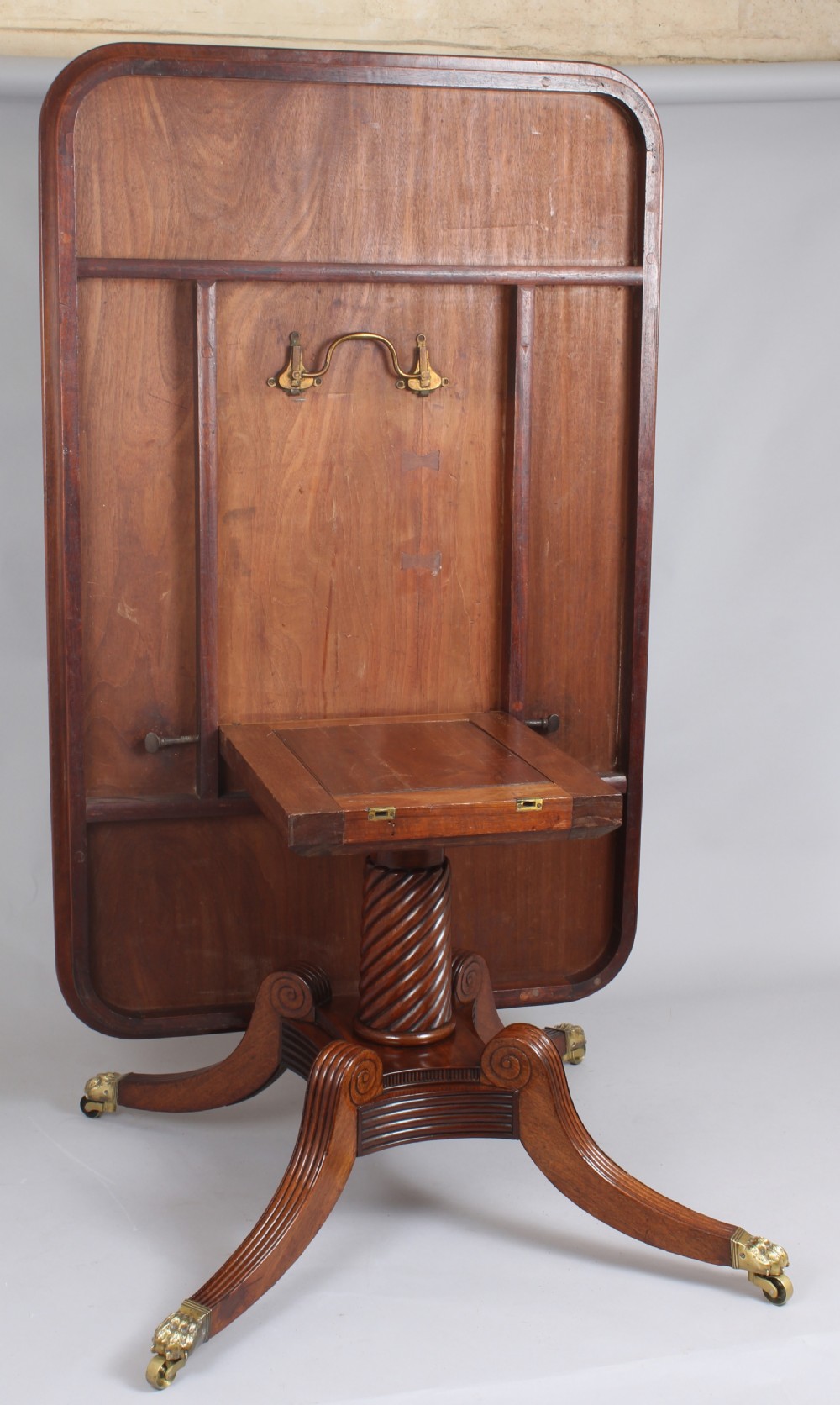 A George IV mahogany breakfast table featuring a polished rectangular top with rounded corners, supported by a spiral-carved pedestal and four reeded legs with brass lion paw castors. View IV