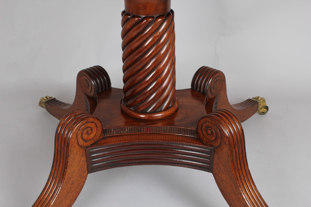 A George IV mahogany breakfast table featuring a polished rectangular top with rounded corners, supported by a spiral-carved pedestal and four reeded legs with brass lion paw castors. View VI