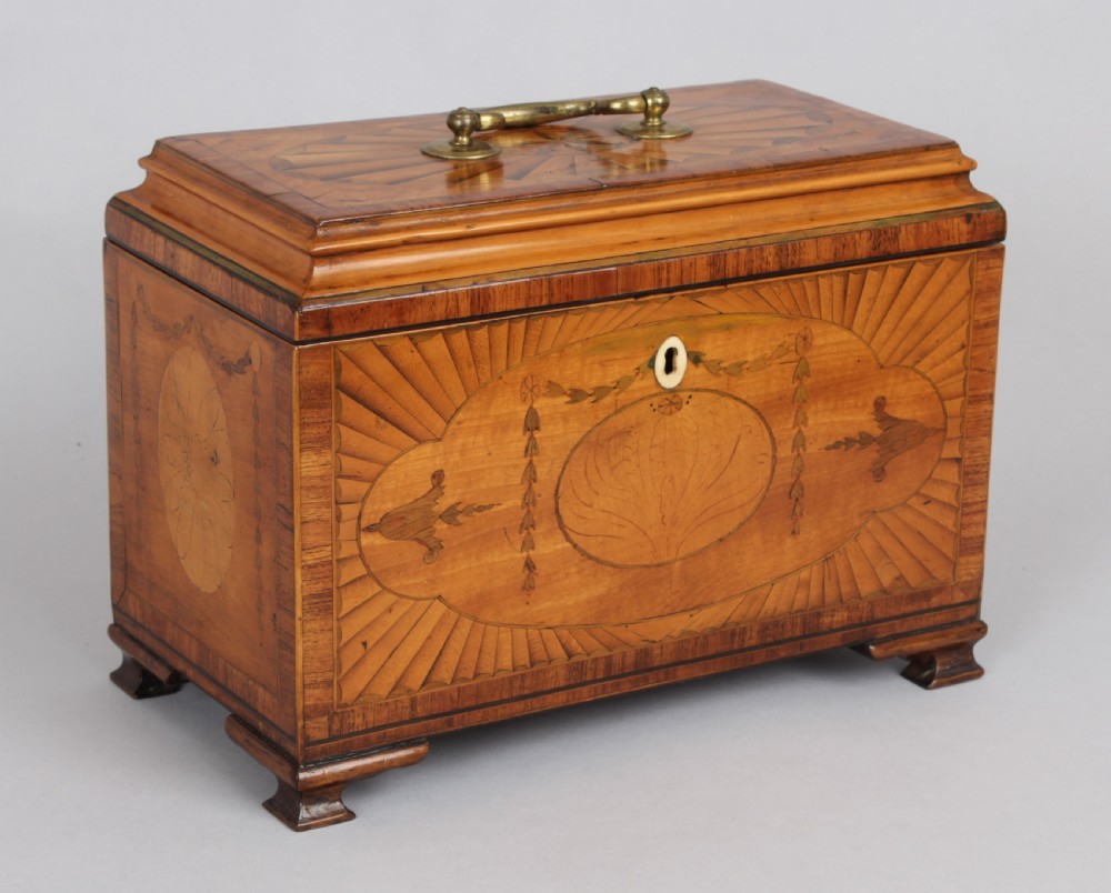 A George III rectangular satinwood tea caddy featuring marquetry oval medallions, fan patterns, a brass top handle, and bracket feet.