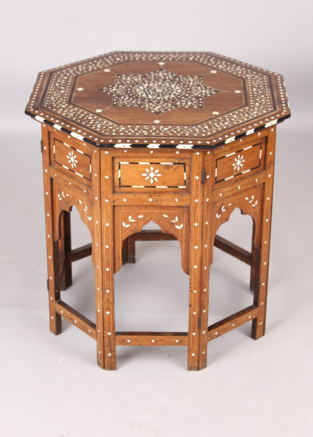 A nineteenth-century octagonal Anglo-Indian side table crafted from warm brown hardwood with elaborate floral star bone inlay and arched panel bases.