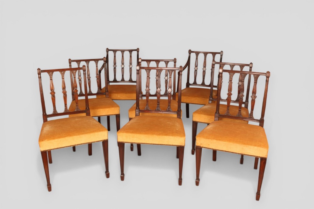 A set of eight mahogany dining chairs featuring carved spindle backs and mustard yellow velvet upholstered seats.