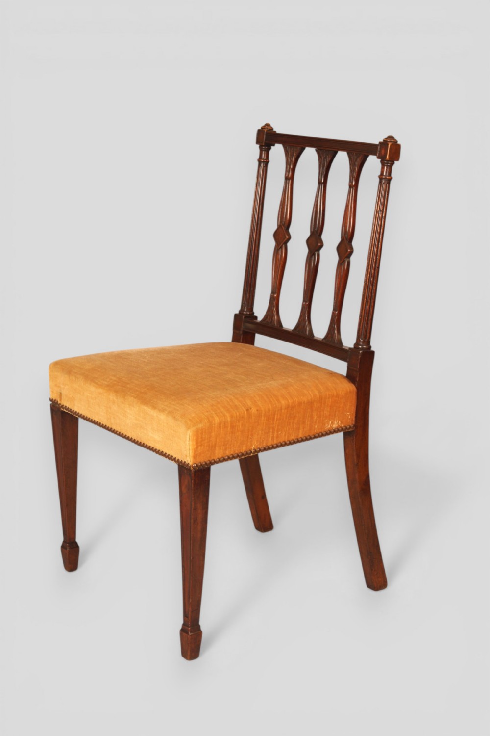 A set of eight mahogany dining chairs featuring carved spindle backs and mustard yellow velvet upholstered seats. View II