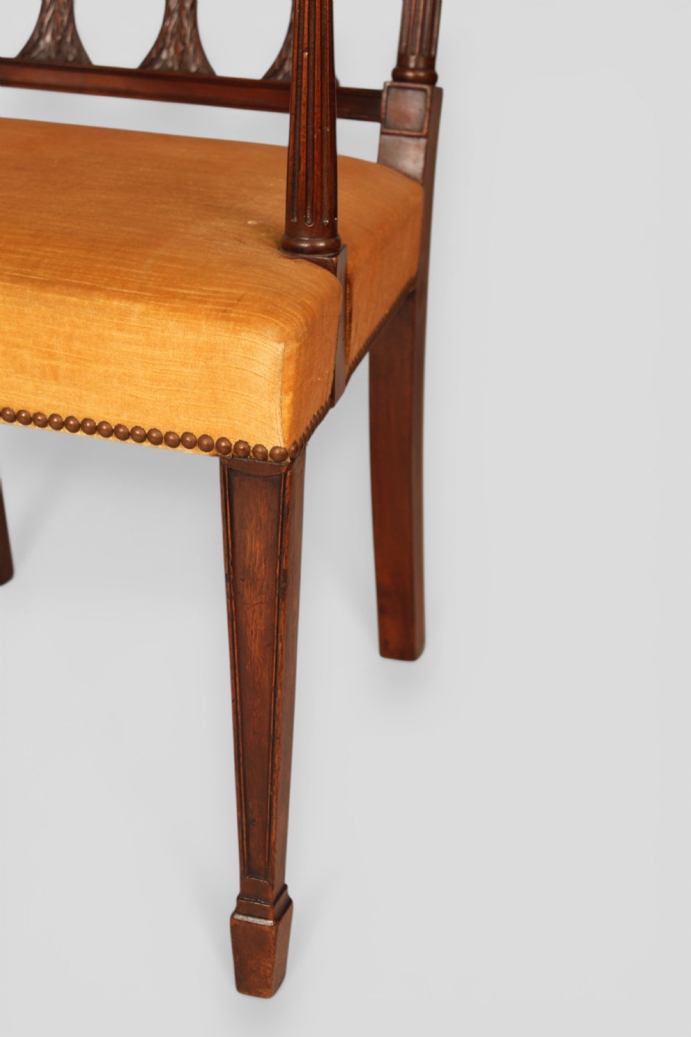 A set of eight mahogany dining chairs featuring carved spindle backs and mustard yellow velvet upholstered seats. View VI