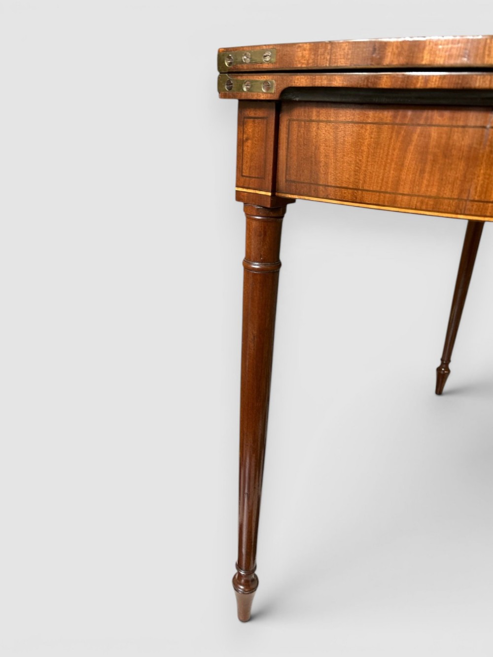 An early 19th-century mahogany demilune card table featuring satinwood crossbanding and turned tapered legs. View IV