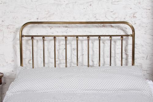 fig 4. An antique French all-brass double bed frame featuring a rounded headboard and footboard with slender vertical spindles set on castor wheels.