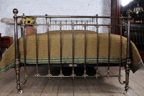 fig 2. An antique Victorian brass king-size bedstead featuring vertical tubular spindles, decorative cast connectors, top rail ball finials, and original white ceramic castors.