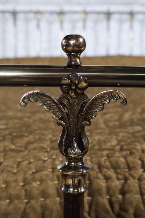 fig 4. An antique Victorian brass king-size bedstead featuring vertical tubular spindles, decorative cast connectors, top rail ball finials, and original white ceramic castors.