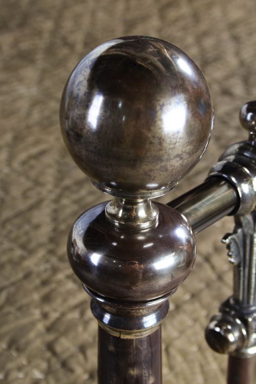 fig 6. An antique Victorian brass king-size bedstead featuring vertical tubular spindles, decorative cast connectors, top rail ball finials, and original white ceramic castors.